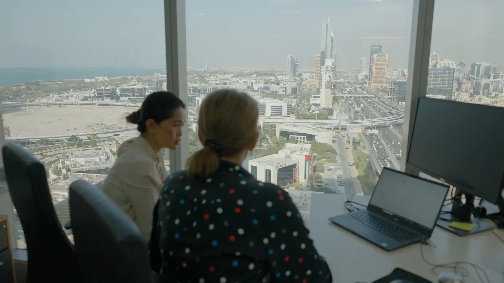 Two people talking in a meeting room with a city skyline in the background